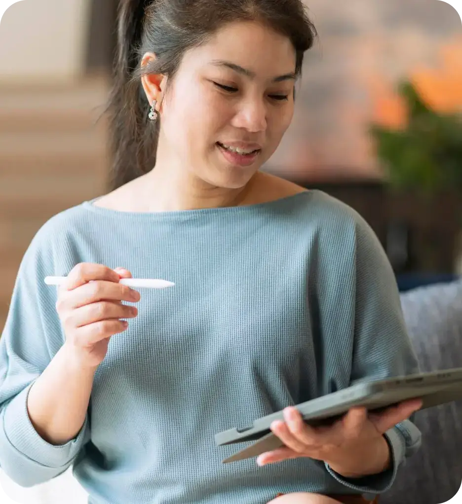 A woman on a couch, holding a tablet, representing a serene moment of interaction with technology in a cozy setting.