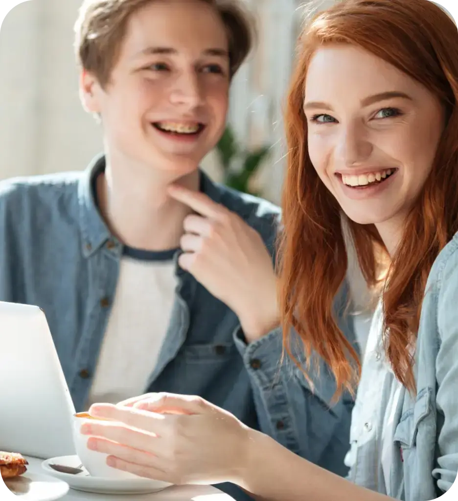 A young man and woman are at a table, appearing relaxed and engaged in a friendly discussion.
