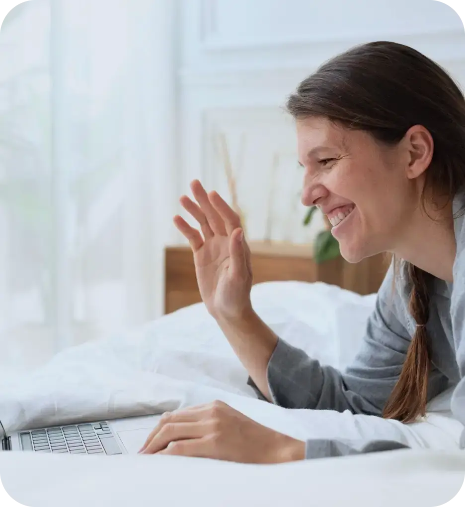 A woman is seen laughing heartily as she uses her laptop, capturing a moment of joy and engagement with digital content.