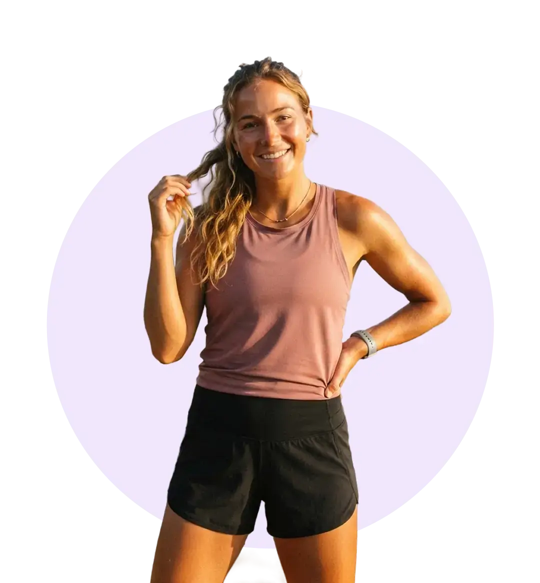 A woman wearing a pink tank top and black shorts stands confidently, showcasing a casual summer outfit.