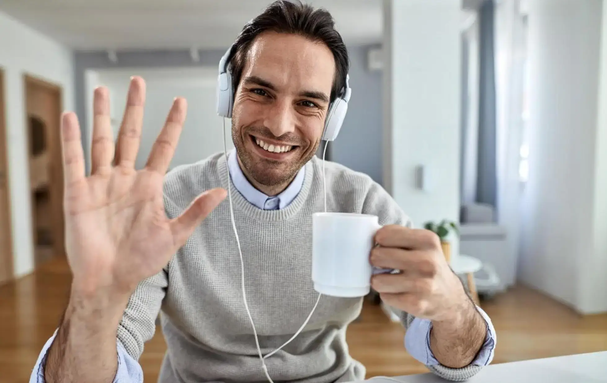 A man listens to music through headphones while holding a cup of coffee, embodying a moment of leisure.