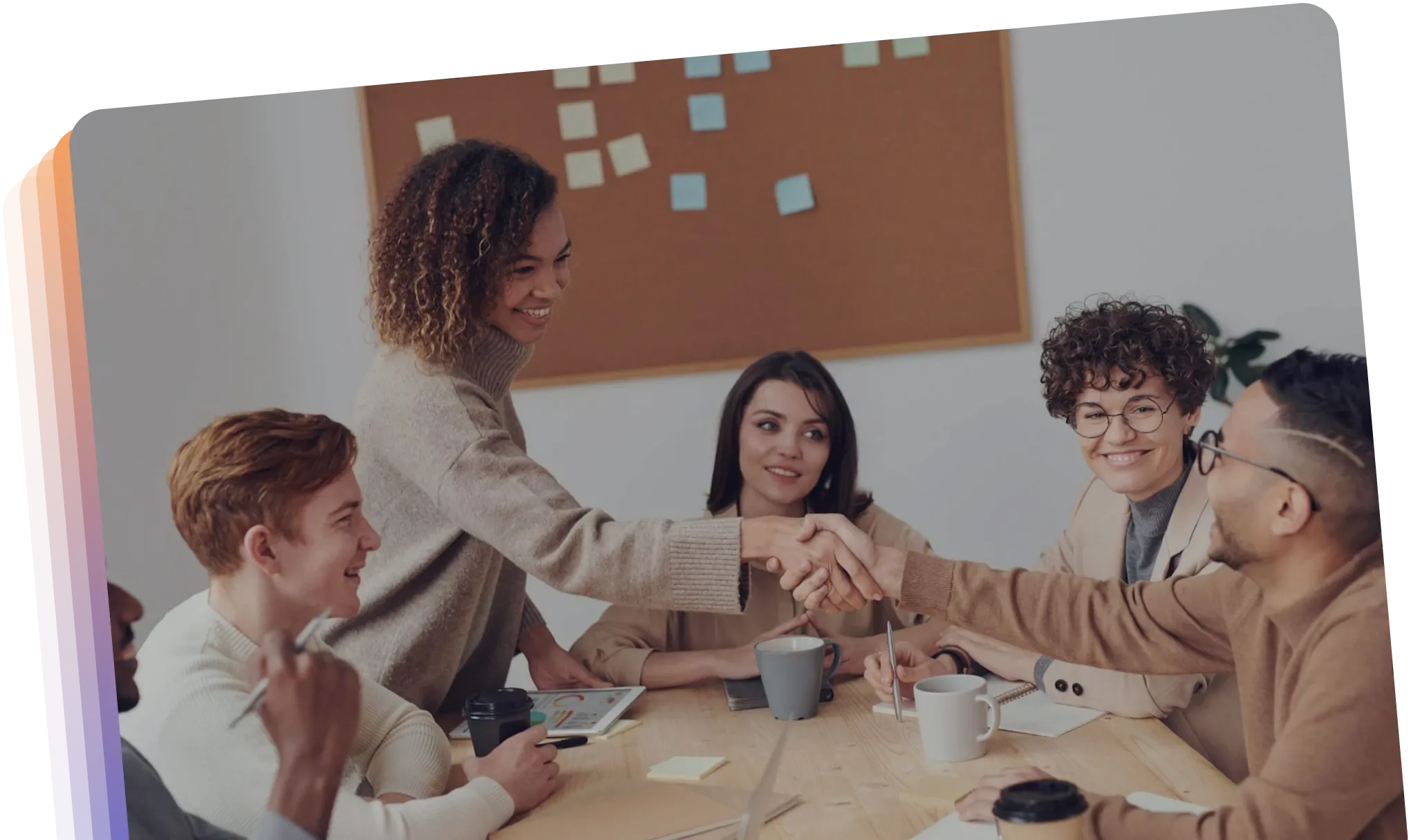A diverse group of individuals shaking hands around a conference table, symbolizing collaboration and agreement.