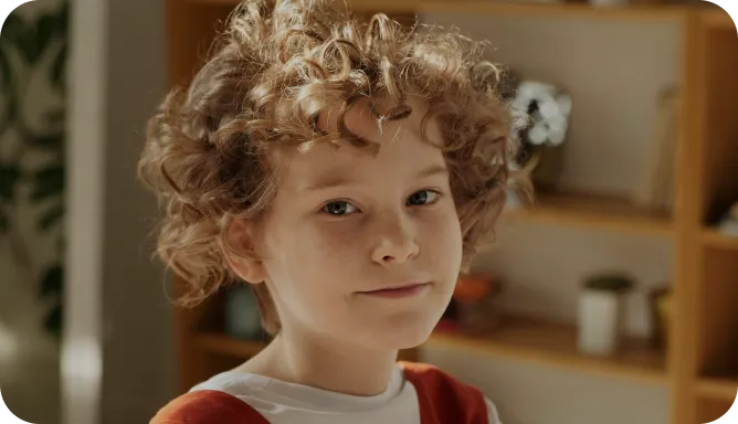 A young boy engaged with a laptop at a table, displaying concentration and curiosity.